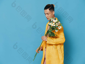 时尚男人。黄色的外套持有花束白色花亚洲外观模型