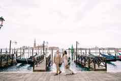 新娘新郎走贡多拉码头持有手威尼斯广场三马可俯瞰三乔治?更大日落天空最大贡多拉码头威尼斯意大利