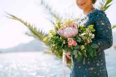 新娘时尚的灰色的衣服站婚礼花束海滨特写镜头
