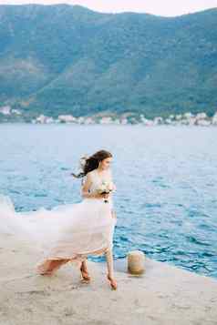新娘持有花束玫瑰手走码头湾肮脏的