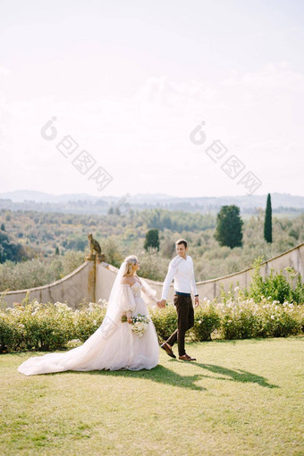 新娘新郎走公园婚礼酒庄别墅托斯卡纳意大利轮婚礼拱装饰白色花绿色植物前面古老的意大利体系结构