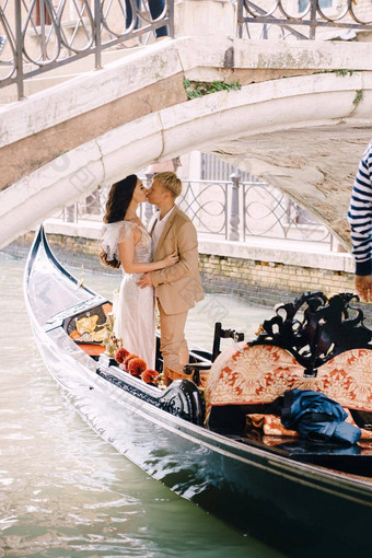 意大利婚礼威尼斯用凤尾船运送卷新娘新郎经典木贡多拉狭窄的威尼斯运河贡多拉浮点数石头桥新婚夫妇吻