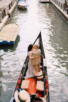 意大利婚礼威尼斯用凤尾船运送卷新娘新郎经典木贡多拉狭窄的威尼斯运河新婚夫妇站船后视图