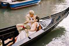 意大利婚礼威尼斯新娘新郎骑经典木贡多拉狭窄的威尼斯运河特写镜头拥抱新婚夫妇