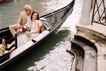 意大利婚礼威尼斯新娘新郎骑经典木贡多拉狭窄的威尼斯运河特写镜头拥抱新婚夫妇