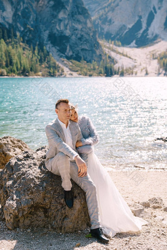 新娘新郎坐拥抱背景石头泻湖布雷斯意大利目的地婚礼欧洲布雷斯湖爱的新婚夫妇走背景令人惊异的自然
