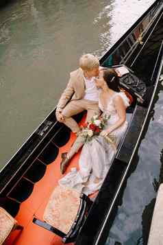 意大利婚礼威尼斯用凤尾船运送卷新娘新郎经典木贡多拉狭窄的威尼斯运河新婚夫妇坐着船背景古老的建筑