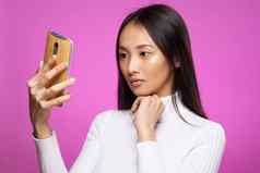 亚洲女人持有电话沟通技术互联网粉红色的背景