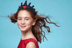 女孩卷曲的头发皇冠头红色的衣服微笑蓝色的背景