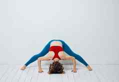女人靠向前木地板上瑜伽体育运动健身体式