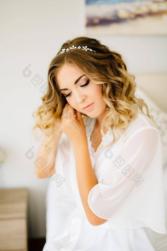 新娘穿白色浴袍把耳环准备婚礼