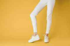 女人的腿白色裤子运动鞋时尚衣服奢侈品街风格黄色的背景