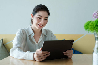 微笑年轻的亚洲女人企业家检查订单数字平板电脑坐着首页办公室工作首页概念