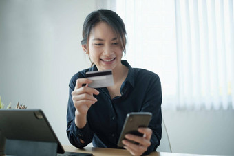 女人休闲衬衫支付信贷卡在线使订单应用程序细胞电话成功的快乐业务女人使事务移动银行应用程序