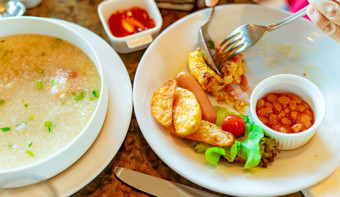 人叉勺子吃早餐餐厅大米<strong>粥</strong>大米<strong>粥</strong>虾白色碗香肠土豆片炸早餐餐健康的生活健康的食物
