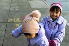 女孩子双胞胎穿紫色的外套可爱的阀盖手套玩