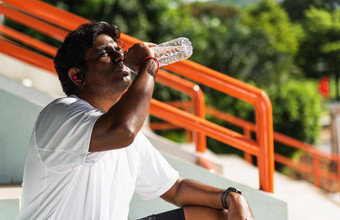 年轻的体育运动跑步者黑色的男人。穿运动员耳机喝水瓶