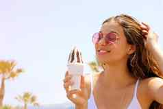微笑美丽的女孩太阳镜海滩吃冰奶油棕榈树背景夏天假期概念