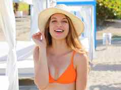 快乐微笑女人长头发摆姿势海滩穿着橙色比基尼前不错的稻草他