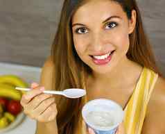 年轻的女人吃光希腊酸奶首页关闭健康的概念