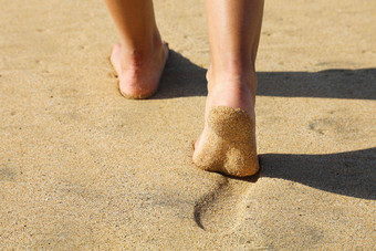 海滩女人腿脚走光着脚沙子离开的足迹金沙子日落假期旅行自由人放松夏天