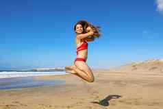 无忧无虑的健康的比基尼女人跳海滩快乐微笑女孩跳自由幸福免费的身体假期重量损失成功健康的生活方式概念