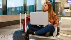 年轻的旅行者女人移动PC机场坐着交叉腿窗户