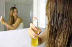 女人应用石油面具喷雾头发前面镜子头发护理概念焦点头发