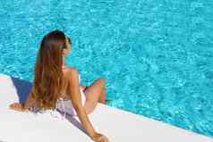 享受假期回来视图苗条的年轻的女人太阳镜白色泳衣游泳池