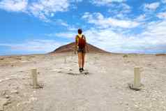 年轻的徒步旅行者女人走通路红色的山蓝色的天空白色云tenerife低角
