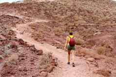 年轻的徒步旅行者女人攀爬山红色的地面tenerife