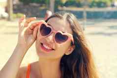 漂亮的浅黑肤色的女人女人粉红色的心洛丽塔太阳镜海滩假期假期旅行自由概念美丽的快乐女孩心形状的太阳镜海滩