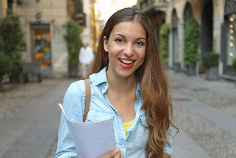 快乐的有吸引力的年轻的女人背包论文站微笑街