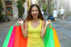 兴奋快乐年轻的女人显示色彩斑斓的购物者袋布雷拉社区米兰意大利