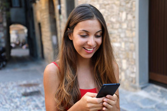 微笑女人移动电话应用程序玩视频游戏在线城市女人放松城市生活方式背景