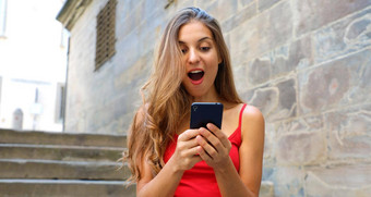 横幅作物广告复制空间背景欧洲小镇石头墙微笑女人移动电话应用程序玩视频游戏在线城市女人放松城市生活方式