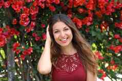 美丽的年轻的女人微笑在户外春天夏天时间红色的花复制空间背景