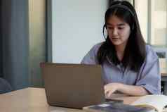 亚洲女孩耳机视频调用遥远的类老师移动PC年轻的学生穿耳机导师研究在线电脑在家教育概念