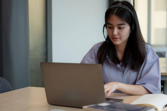 亚洲女孩耳机视频<strong>调用</strong>遥远的类老师移动PC年轻的学生穿耳机导师研究在线电脑在家教育概念