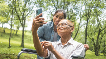 祖父轮椅（外）孙女会说话的视频调用亲戚智能手机公园家庭生活假期