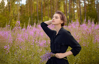 年轻的女孩黑色的衣服自然羽扇豆花美粉红色的花