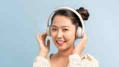快乐可爱的年轻的女人耳机听音乐蓝色的背景