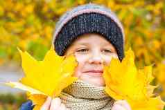 秋天情绪男孩持有黄色的枫木叶子手秋天肖像孩子针织他视线可爱的微笑男孩