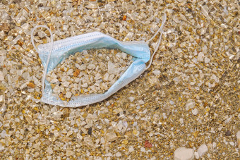 蓝色的医疗脸面具谎言海滩环境海岸塑料污染科维德大流行