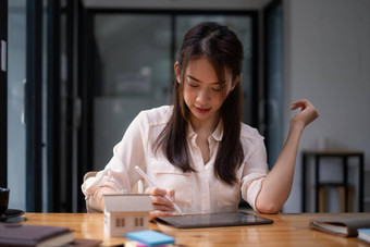 架构师女人数字平板电脑应用程序手绘设计房子模型木桌子上财产的想法真正的房地产