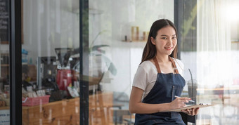 快乐的微笑年轻的亚洲女人企业家咖啡商店计数器订单列表