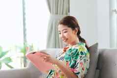 快乐年轻的女人阅读故事书沙发上首页