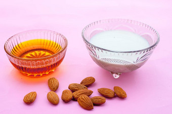 牛奶杏仁脸包孤立的粉红色的表面生牛奶杏仁蜂蜜混合玻璃碗ex-foliate皮肤