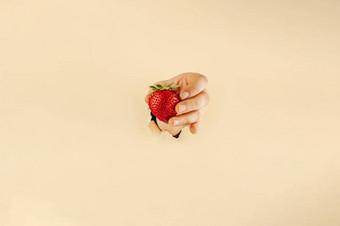 女孩持有手指红色的成熟的草莓女人的<strong>手撕</strong>裂纸持有浆果在线购物概念