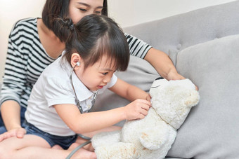 亚洲女孩玩婴儿娃娃玩具亚洲女孩持有听诊器手检查婴儿娃娃玩具